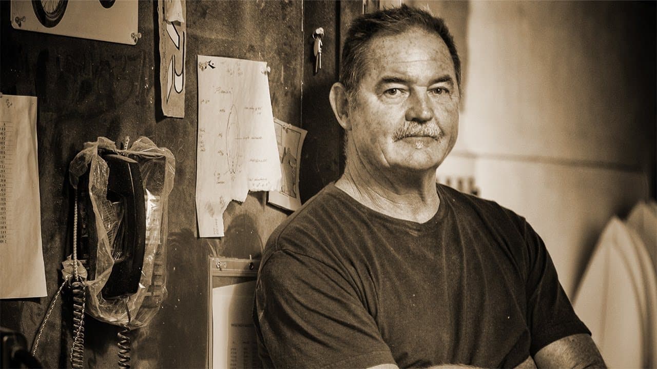 A surfboard shaper in his workshop, arms crossed
