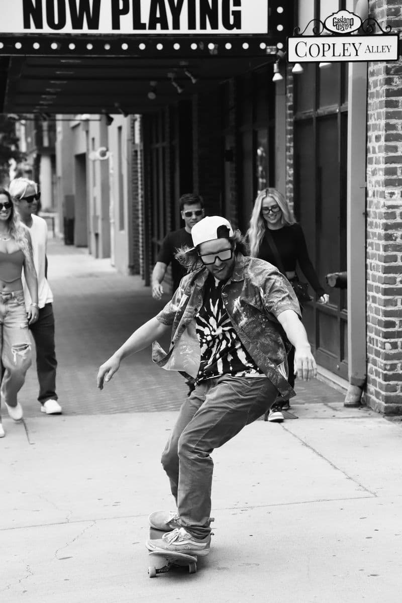 A skateboarder mid-trick under a cinema marquee, in black and white