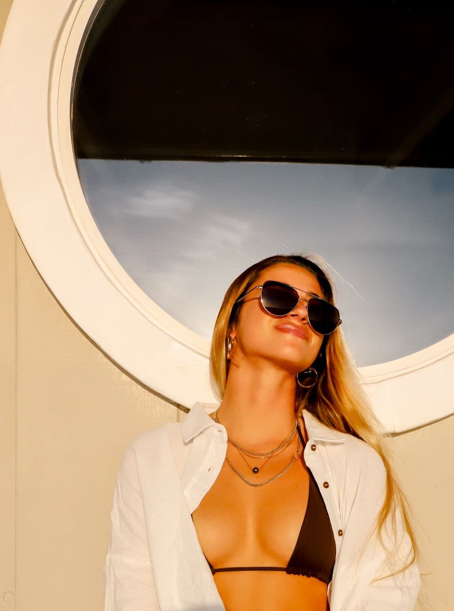 A model in CARVE sunglasses in warm evening light, framed by a round window