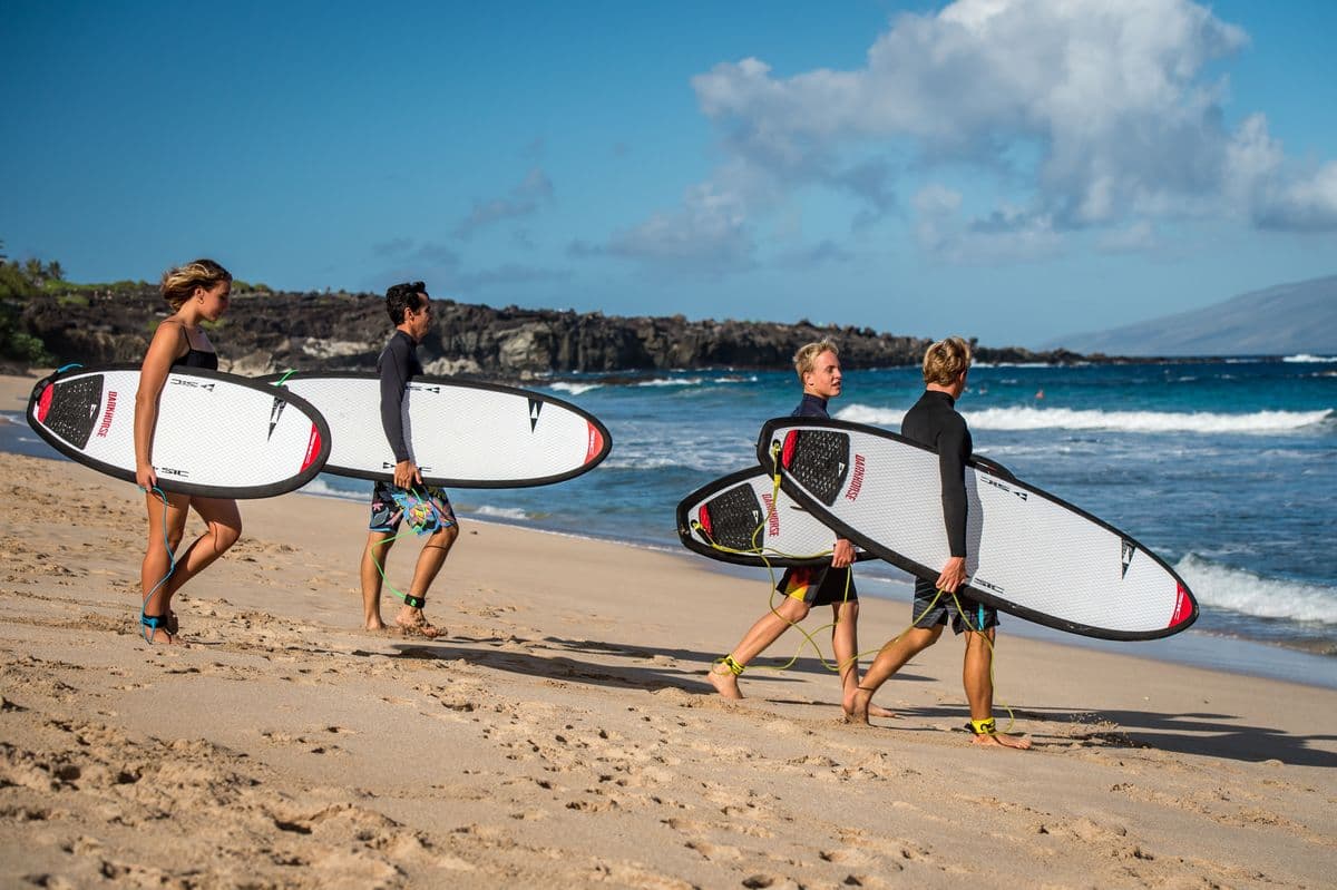 Riders carrying boards along a beach