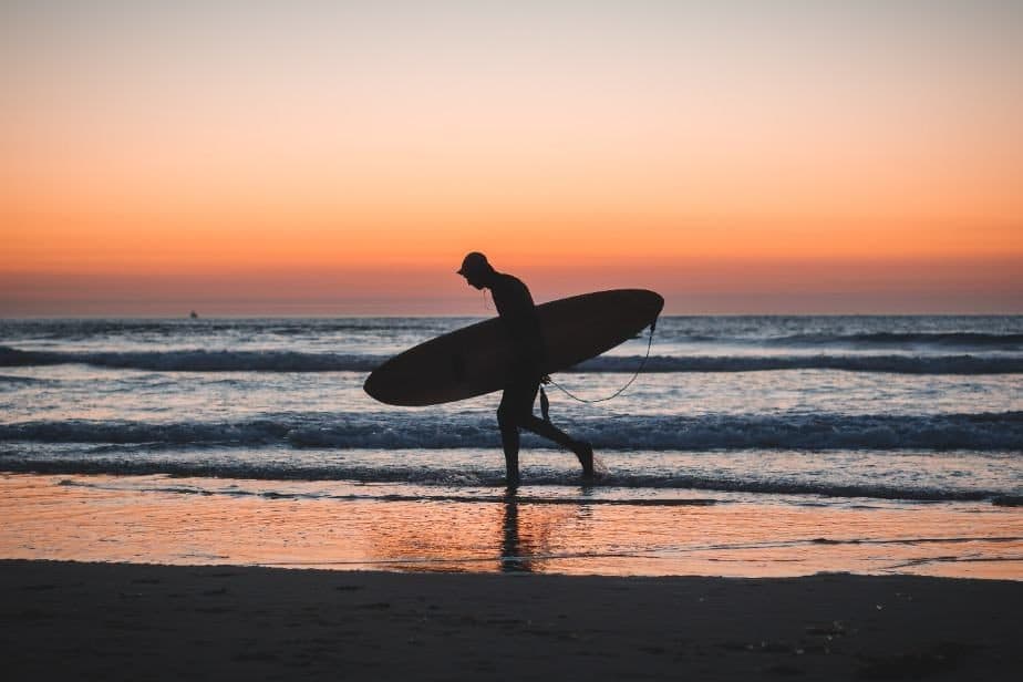 A surfer silhouetted on the shore at dusk